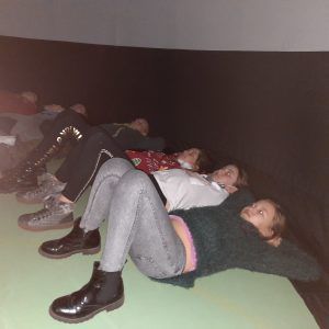 Oglądacjący film uczniowie położyli się na podłodze podpierając głowy, by przestrzeń oceanu obejrzeć z całej perspektywy