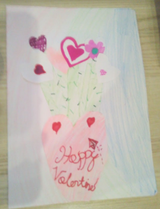 Kartka ozdobiona własnoręcznie narysowanymi kolorowymi serduszkami i napisem Happy Valentines.