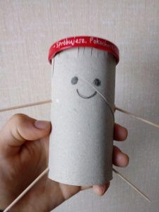 praca przedstawia ludzika wykonanego z papierowej rolki, wykałaczek bedących rączkami i nóżkami a czapeczką jest metalowa nakrętka od słoiczka