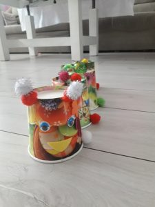 praca prezentuje gąsiennicę wykonaną z kolorowych kartonowych kubeczków ozdobioną pomponikami