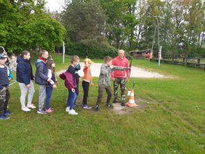 grupa uczniów oczekuje w kolejce do strzelania z łuku