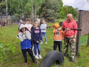 grupa uczniów obserwuje kolegę strzelającego z wiatrówki