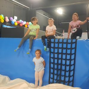 Na zdjęciu widać 4 dziewczynki z klas 1-3. Skaczą do basenu z gąbkami.