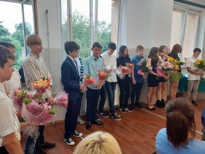 zdjęcie przedstawia ósmoklasistów z bukietami kwiatów