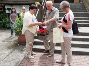 dwoje nauczycieli wręcza nauczycielce kosz z kwiatami