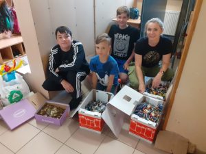 zdjęcie przedstawia nauczyciela i trzech uczniów z zebranymi w kartonach bateriami i monetami