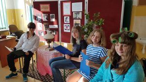 Zdjęcie przedstawia występujących uczniów tuż po ukończeniu czytania. Uśmiechnięci przyjmują brawa.