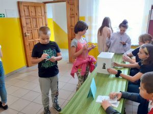 Grupa uczniów wypełnia karty wyborcze.