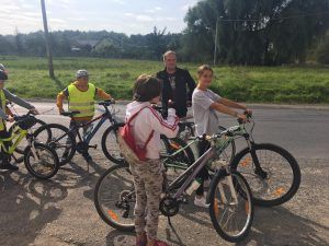 Zdjęcie przedstawia 4 rowerzystów i ich opiekuna odpoczywających przed sklepem w miejscowości Buchałów.