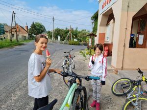 Zdjęcie przedstawia 2 rowerzystki odpoczywające przed sklepem w miejscowości Buchałów.