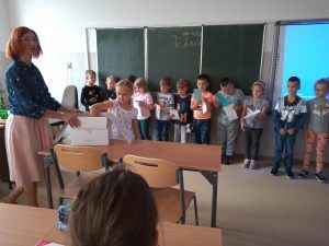 Uczniowie klasy pierwszej podchodzą do nauczyciela i z kartonowego pudełka losują zakładki do książek.