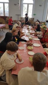 Dzieci przy długim stole kosztują ziemniaczane potrawy.