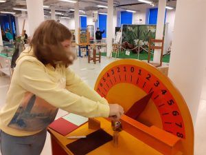 Uczennica mierzy siłę przy zegarze.