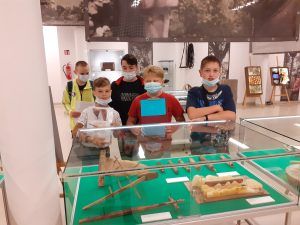 Pięciu uczniów przed gablotą z eksponatami.