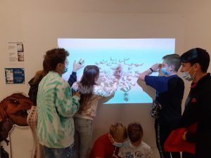 Kilkoro uczniów odkrywa dinozaura na tablicy interaktywnej.