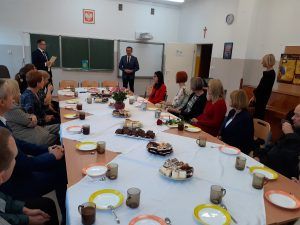Nauczyciele siedzą przy uroczyście nakrytym stole. Słuchają wystąpienia Przewodniczącego Rady Gminy Świdnica.
