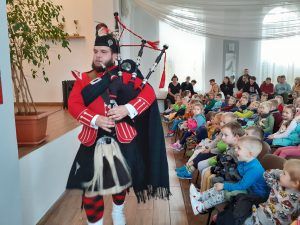 Sala wiejska w Słonem. Na scenie koncertuje dudziarza ubrany w tradycyjny strój szkocki. Na widowni dzieci ze szkoły w Słonem obserwują koncert.