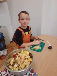 Chłopiec kroi owoce do sałatki.