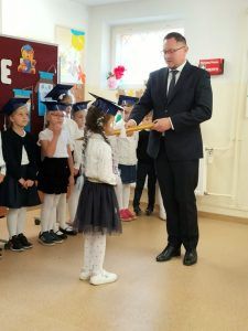 Dyrektor pasuje na uczennicę dziewczynkę z klasy pierwszej.