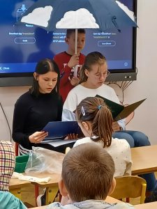 Uczennice klasy siódmej czytają w klasie drugiej legendę lubuską pt. "Trzy gąski".