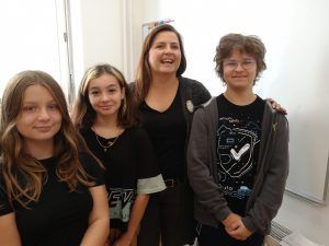 Grupa trojga uczniów i nauczycielki z uśmiechami na twarzy.