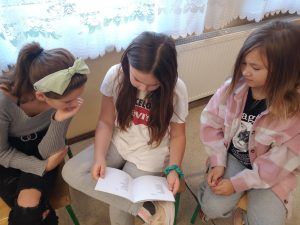 Trzy uczennice przeglądają książkę.