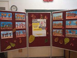 Zdjęcie przedstawia tablicę z plakatem "Dobre Książki" oraz dekoracją jesienną.