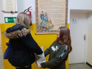 uczennica częstuje cukierkiem koleżankę ze szkoły