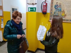 uczennica częstuje nauczyciela cukierkiem