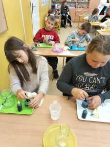 Na zdjęciu uczennice klasy trzeciej dodają pigment za pomocą próbówek