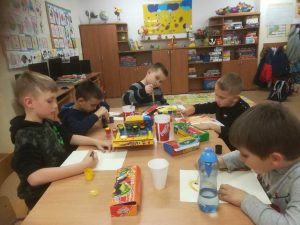 grupa uczniów wykonujących prace plastyczne o misiach