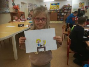 zdjęcie przedstawia dziewczynkę z rysunkiem wróżby