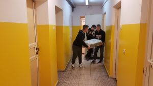 trzech uczniów niosących zużyty sprzęt elektryczny