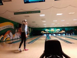 Na fotografii 3 dziewczynka obserwuje kulę toczącą się w kierunku kręgli.