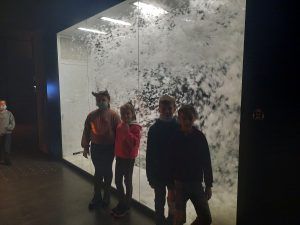 na zdjęciu dzieci na tle wirującego śniegu w szklanym pojemniku