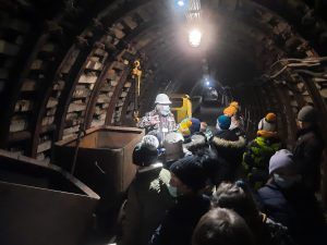 dzieci wraz przewodnikiem w podziemnych korytarzach