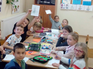 dzieci przy stole przygotowują kartki świąteczne