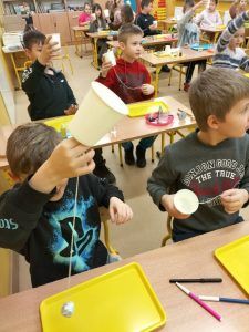 chłopcy wykonują doświadczenie z kubeczkami