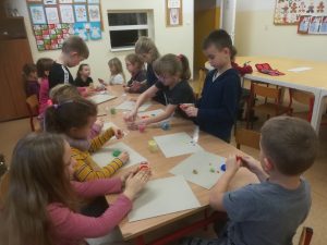 grupa dzieci przy stolikach podczas prac plastycznych