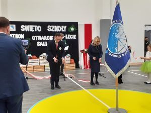 Dyrektor szkoły i dwoje gości przecinają wstęgę oznaczającą otwarcie sali