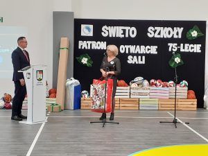 na zdjęciu dyrektor sąsiedniej szkoły wręczający prezent z okazji uroczystości