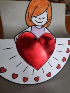 na kartce rysunek dziewczynki trzymającej czerwone serce