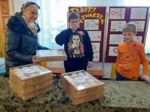 na zdjęciu uśmiechnięta pani z uczniami przy kartonach z pączkami