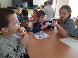 troje uczniów zajadających pączki