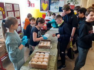 grupa uczniów przy stolikach z pączkami