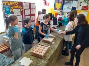 grupa uczniów przy stolikach z pączkami