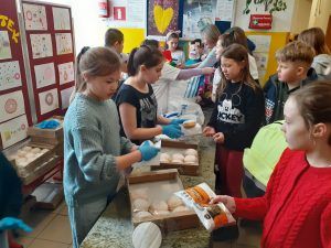 grupa uczniów przy stolikach z pączkami