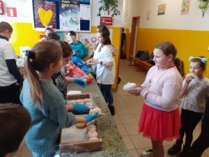 grupa uczniów przy stolikach z pączkami