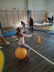 uczniowie na sali gimnastycznej podczas pokonywania toru przeszkód