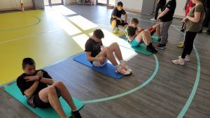 trzech uczniów wykonujących brzuszki